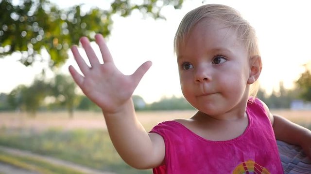 Cute little baby girl on nature sway hand to parent in slow motion