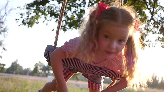 Little cute blonde child girl fail - sway lying on swing fall unexpectedly on a grass