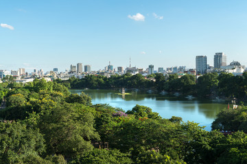 Hoan Kiem lake or Sword lake, Ho Guom in Hanoi, Vietnam with Turtle Tower, green trees and buildings on horizon