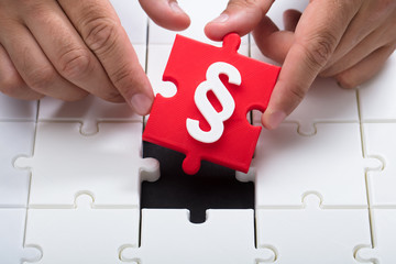 Person connecting last red piece into jigsaw puzzles
