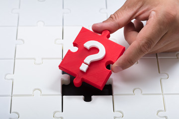 Person placing question mark piece into jigsaw puzzle