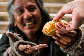 Hand giving bread or food to blurred happy face homeless male