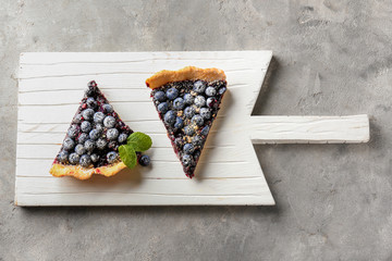 Wooden board with pieces of delicious blueberry pie on table - obrazy, fototapety, plakaty