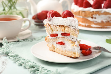 Plate with piece of delicious strawberry cake on table