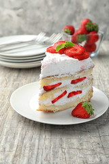 Plate with piece of delicious strawberry cake on wooden table