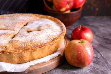 Naklejka na ściany i meble Board with delicious apple pie on dark table, closeup