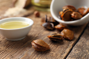 Bowl with apricot essential oil on wooden table