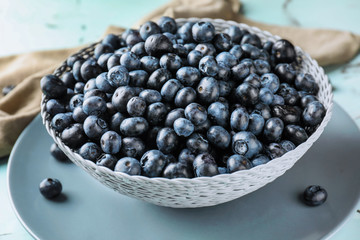 Bowl with ripe blueberries on light table, closeup