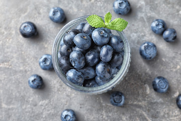 Glass jar with ripe blueberries on light table