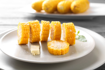 Plate with cut boiled corncobs on table, closeup
