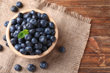 Obraz na płótnie Canvas Bowl with ripe blueberries on wooden table
