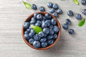 Bowl with ripe blueberries on wooden table