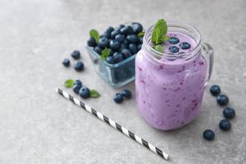 Mason jar of tasty blueberry smoothie on light table