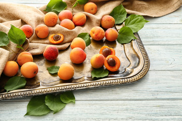 Tray with fresh apricots on wooden table
