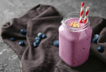 Glass jar of tasty blueberry smoothie on table