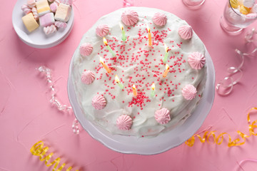 Tasty birthday cake with burning candles on color table