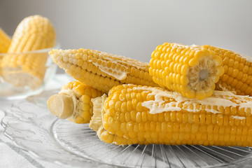 Tasty corn cobs with butter on glass plate, closeup