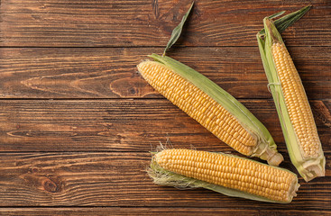 Fresh corn cobs on wooden background