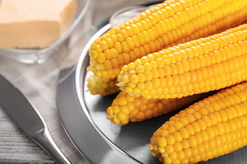 Plate with tasty corn cobs on table, closeup