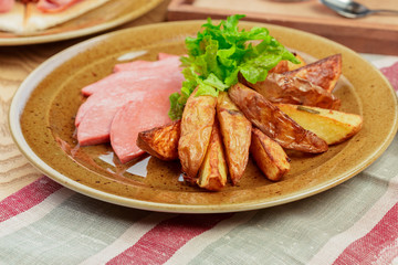 Roasted potatoes with ham slices close up