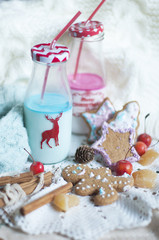 Christmas milk in bottles and holiday sweets. New Year party. Colored milk and straws,