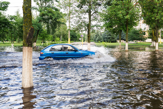 The car driving on a flooded road during a flood caused by heavy rain