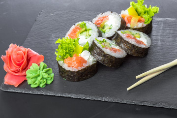 Japanese restaurant, sushi roll on black slate plate.