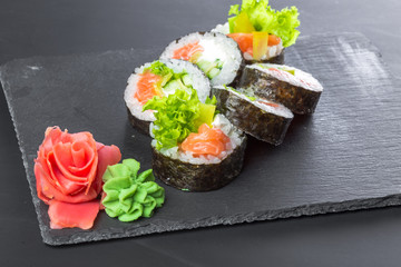 Japanese restaurant, sushi roll on black slate plate.