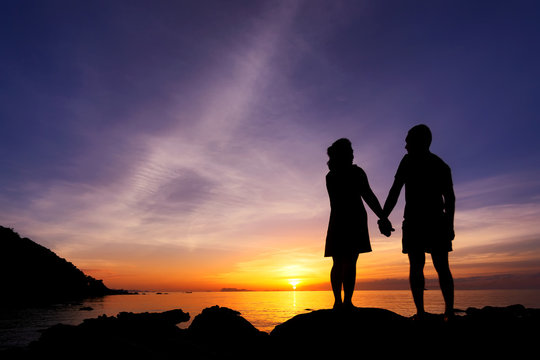 Silhouette of couple hold one's hands on the beach