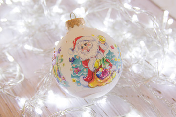 Christmas or New Year background: fur-tree branches, colorful glass balls, decoration and glittering stars on white wood, top view, copy space.