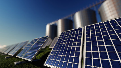 Obraz premium Solar Farm with Silos Behind on a Bright Day