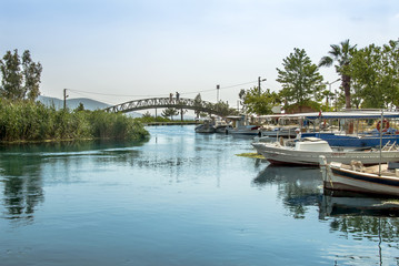 Fototapeta na wymiar Mugla, Turkey, 14 May 2012: Bridge and Boats at Azmak Stream, Gokova Bay, Akyaka