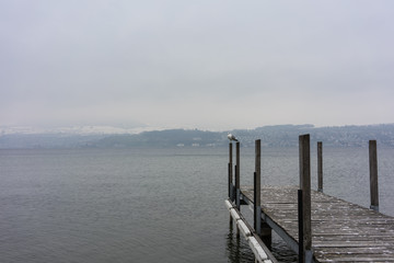 empty wood pier on lake in winter with fog