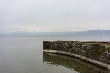 Obraz premium stone harbour at lake in winter with snow mountain landscape