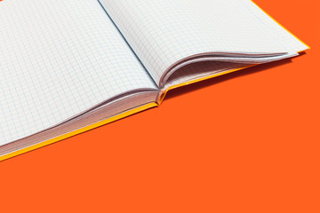 white opened workbook lying on an orange background. concept of business or educational equipment. free space for advertising text