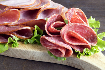 slices of French cheese-dried salami with spices on wooden background