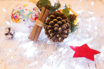 Christmas or New Year background: fur-tree branches, colorful glass balls, decoration and glittering stars on white wood, top view, copy space.
