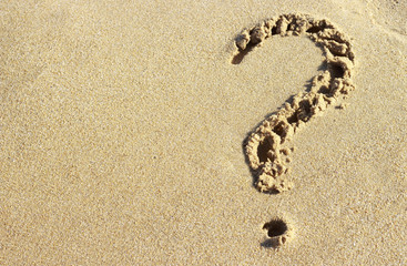 Fototapeta na wymiar question mark drawn on a sandy beach, close-up, top view