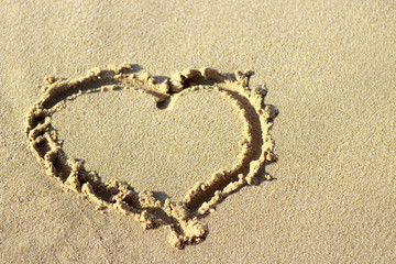 heart drawn on sand, top view. Beach background