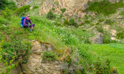 Girl with a backpack in the mountains. Trekking on a mountain road. Panorama of the mountain valley.
