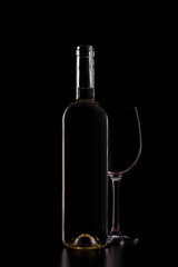 Silhouette of white wine bottle with empty half glass isolated on black dark background with soft reflections and beautiful shadows. Studio shot.