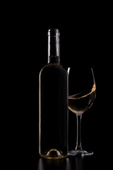 Silhouette of white wine bottle with half glass isolated on black dark background with soft reflections and beautiful shadows. Studio shot.