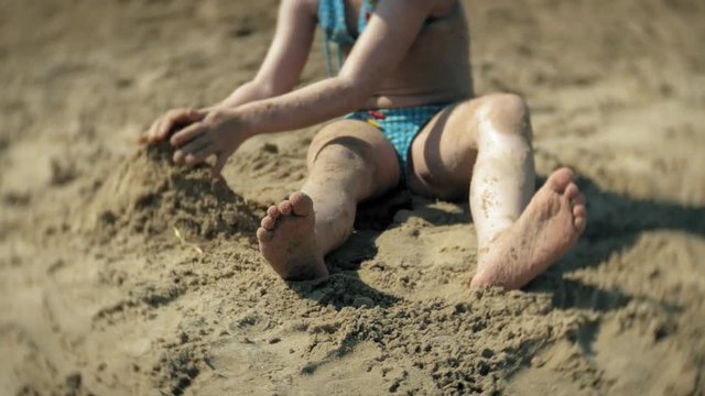 baby girl playing on the beach with sand