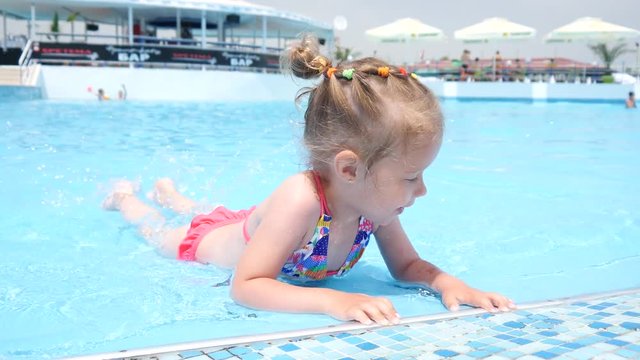 Cute little child girl have fun swim in swimming pool water at summer resort