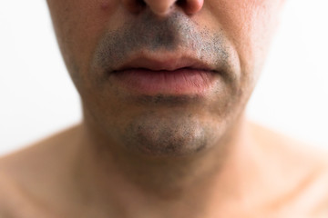 Obraz premium mouth of a man with a shaved beard. detail of the lips in the foreground with blurred white background. lower part of a white man's face