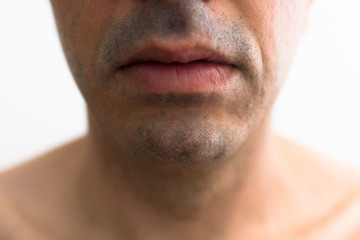 Obraz premium mouth of a man with a shaved beard. detail of the lips in the foreground with blurred white background. lower part of a white man's face