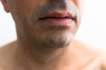 Obraz premium mouth of a man with a shaved beard. detail of the lips in the foreground with blurred white background. lower part of a white man's face