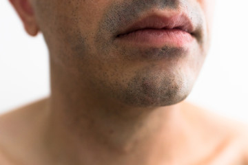 Obraz premium mouth of a man with a shaved beard. detail of the lips in the foreground with blurred white background. lower part of a white man's face