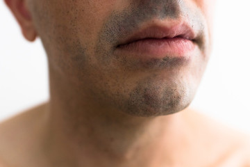 Obraz premium mouth of a man with a shaved beard. detail of the lips in the foreground with blurred white background. lower part of a white man's face
