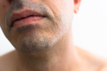 Obraz premium mouth of a man with a shaved beard. detail of the lips in the foreground with blurred white background. lower part of a white man's face